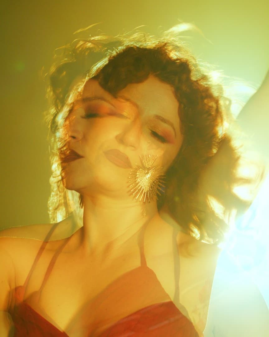 Alexandra Raia, cantante y compositora italiana en Barcelona, sobre el escenario con luz de foco ámbar